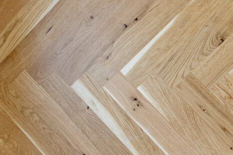 Blick von oben auf helles Fischgrätparkett.