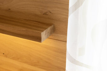 Nahansicht auf holzvertäfelte helle Wand und Wandleuchte in Holz eingelassen.