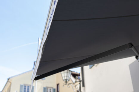 Blick von der Seite auf Unterseite von ausgefahrener Markise, Unterseite der Markise ist in grau-anthrazit gehalten.