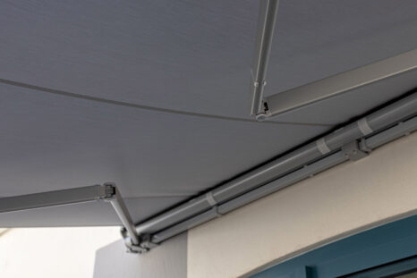 Blick von unten auf weiße Kassettenmarkise, ausgefahren, Gelenkarme weiß lackiert.