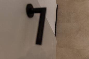 Obendraufansicht heller Mineralboden, schwarze Türklinke im Vordergrund.