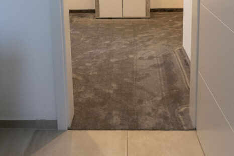 Blick von außen durch Tür in mit frischem Teppich ausgelegtem Zimmer.