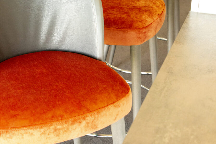 Bild von schräg oben auf zwei frisch aufgepolsterte Barhocker, gut zu sehen sind die beiden orangefarbenen Velourspolster.
