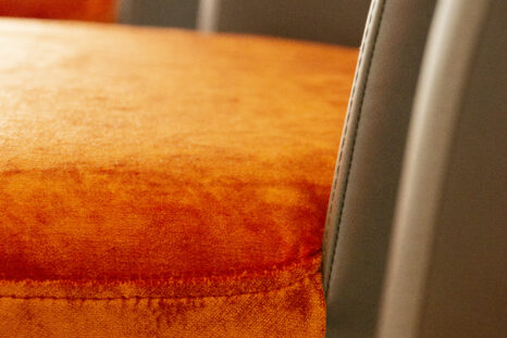 Zoomansicht auf orangenes Velourspolster des frisch aufgepolsterten Barhockers.