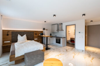 Schlafzimmer neu eingerichtete Ferienwohnung, dunkler Naturholzbettrahmen, weiße Bettwäsche auf dunkelgrauem Spannbetttuch.