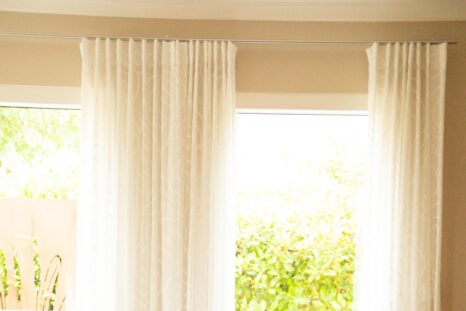 Detailansicht weiße Gardinen vor zwei Fenster, weiße Wände, hoch belichtet.