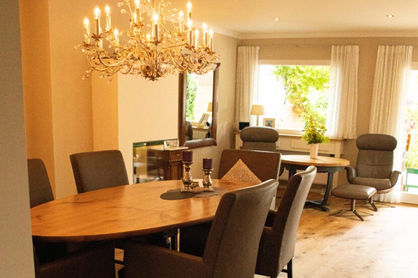 Dreiviertelansicht des frisch renovierten Esszimmers, österreichisches Echtholzparkett, ovaler Echtholztisch mit mehreren dunkelgrauen Lehnenstühlen im Vordergrund.