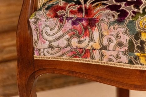 Frisch aufgepolsterter Lehnensessel mit floralem Muster, Detailansicht der Sitzkante und der Armlehne.