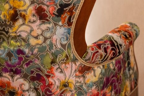 Rückenansicht frisch gepolsterter Sessel mit floralem Muster, Detailansicht vor weißer Wand