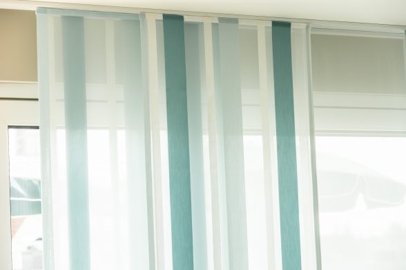 Großansicht von teilweise gerafften, blau-weißen Aeros auf ihrer Schiene, vor weißem Fenster.