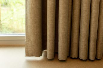 Nahansicht auf den Gardinensaum und den hellen Linoleumboden.