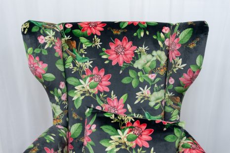 Frontalansicht obere Hälfte von frisch gepolstertem Lehnensessel. Von Haller Raumgestaltung neu mit schwarzem Samt mit Rosa Lotusmuster gepolstert. Auf dem Sessel liegt ein Kissen, ebenfalls mit schwarzem Stoff mit Rosa Lotusmuster.