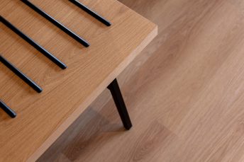 Heller Vinylboden in Holzoptik von schräg oben mit hellem Holztisch.