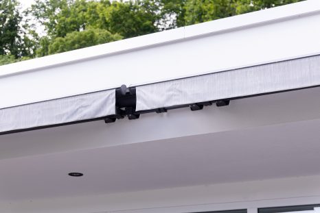 Frontalansicht weißgraue Doppelmarkise, komplett eingefahren vor weißer Hauswand, installiert in Hotel Sennerbad Ravensburg.